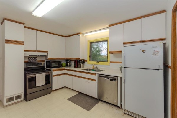 Kitchen with white cabinets, stainless steel stove, microwave, dishwasher, and a yellow-trimmed window. - 331 Memorial Drive, Rivers