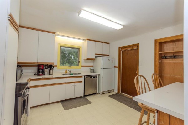 Kitchen with white cabinets, stainless steel appliances, a dining table, and a wooden door. - 331 Memorial Drive, Rivers