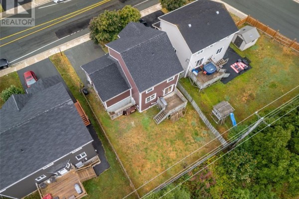 Aerial view looking down at the backyard of a brown house with a wooden deck. - 331 Stavanger Drive, St  John S