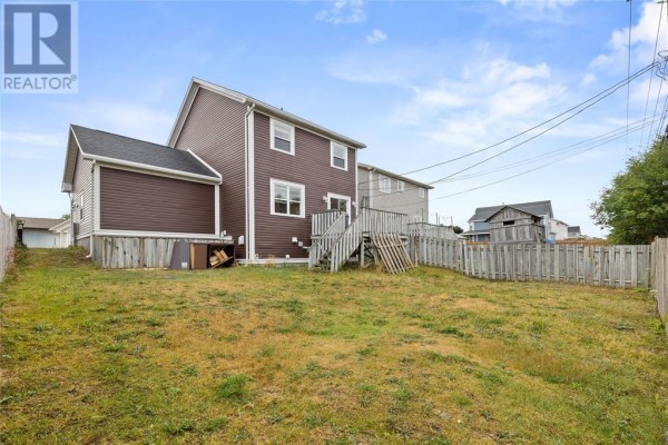 Backyard of a two-story brown house with a wooden deck and a lawn. - 331 Stavanger Drive, St  John S