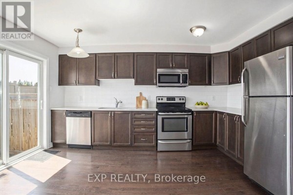 Kitchen with dark brown cabinets, white subway tile backsplash, stainless steel appliances, and a sliding glass door to the backyard. - 331 Willow Aster Circle, Ottawa
