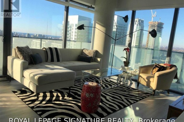 A bright living room with floor-to-ceiling windows, a sectional sofa, and a glass coffee table. - 3310 - 161 Roehampton Avenue, Toronto