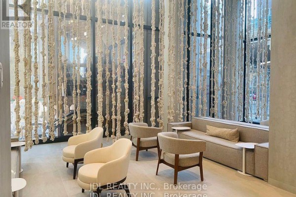 Lobby seating area with light beige upholstered chairs, sofa, and a rope art installation. - 3310 - 55 Cooper Street, Toronto