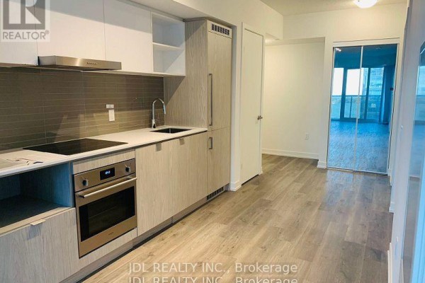 Apartment kitchen with light wood cabinets, grey tiled backsplash, stainless steel appliances, and induction cooktop. - 3310 - 55 Cooper Street, Toronto
