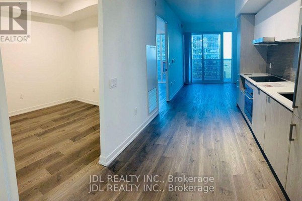 Apartment view showing a modern kitchen, wood flooring, and a living area with a balcony. - 3310 - 55 Cooper Street, Toronto