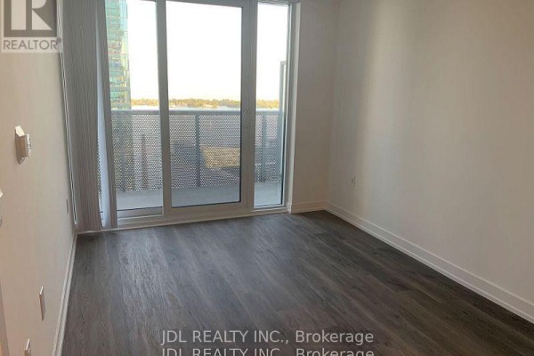 Empty bedroom with grey wood-look flooring and large sliding glass doors opening to a balcony. - 3310 - 55 Cooper Street, Toronto