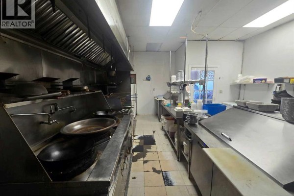 Commercial kitchen showing stoves, ventilation hoods, and prep counters. - 3315 26 Avenue Sw, Calgary