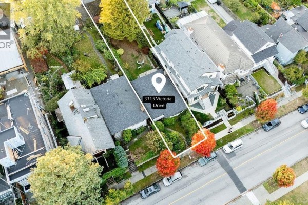 Aerial view of 3315 Victoria Drive, a narrow house with a white border, nestled between two neighboring houses. - 3315 Victoria Drive, Vancouver