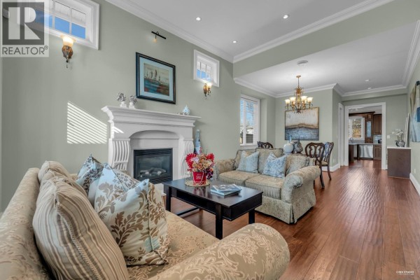 Living room with sofas, fireplace, dining area, and view into the kitchen and hallway. - 3317 Bentinck Place, Richmond