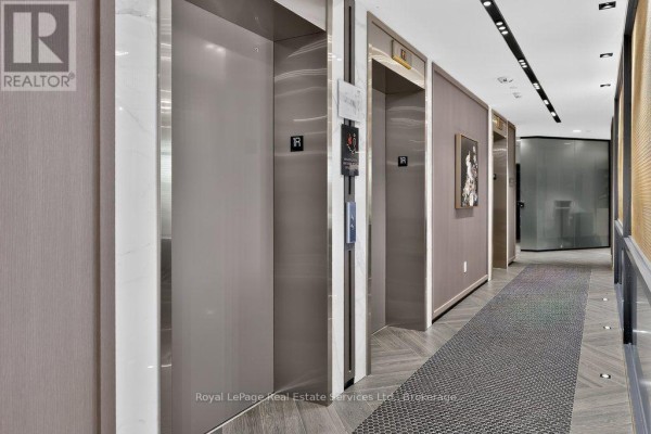 Hallway with multiple elevators and a textured grey carpet runner. - 332 - 405 Dundas Street W, Oakville