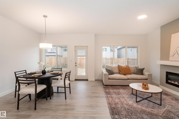 Open concept living and dining area with a round dining table and a sofa near the fireplace. - 332 27 St Sw, Edmonton