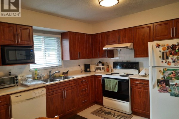 Kitchen with dark cherry cabinets, white countertops, a white stove, and a white refrigerator. - 332 Avalon Drive, Port Moody