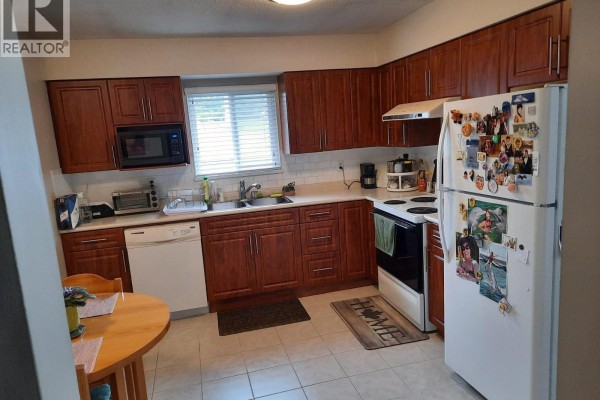 Kitchen with dark cherry cabinets, white countertops, a white stove, and a white refrigerator. - 332 Avalon Drive, Port Moody