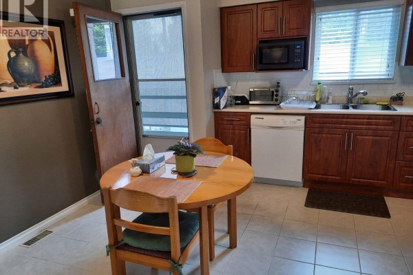 Kitchen area with a small round wooden table, chairs, and adjacent dark cherry cabinetry. - 332 Avalon Drive, Port Moody