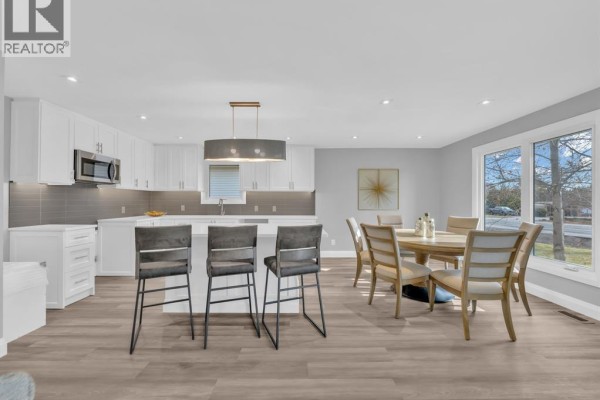 Modern kitchen with white cabinets, island, bar stools, and a dining area. - 332 Heritage Road, Kingsville