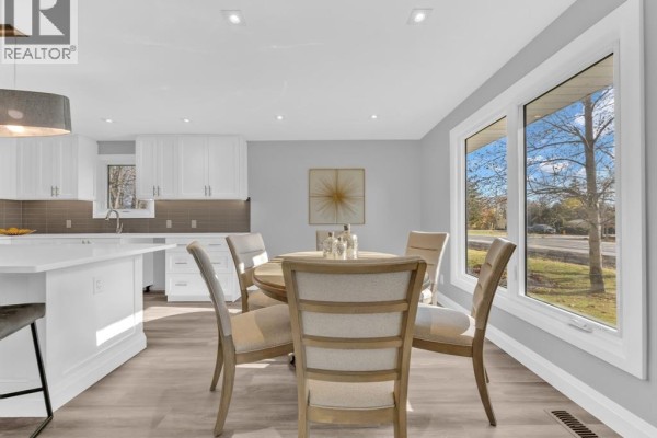 Dining area with a round table, chairs, and large windows overlooking the street. - 332 Heritage Road, Kingsville