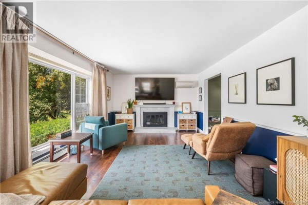 Living room with hardwood floors, fireplace, large window, and modern furniture. - 332 Mcallister Road, Riverview