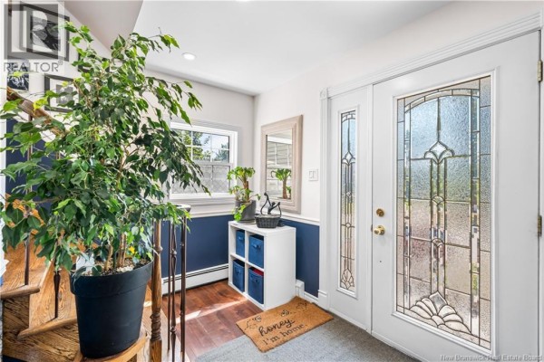 Entryway with glass front doors, wooden staircase, and a large potted plant. - 332 Mcallister Road, Riverview
