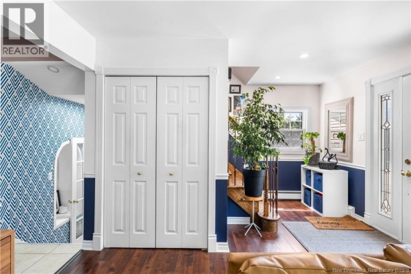 Hallway with double white closet doors, dark blue accent wall, and a staircase. - 332 Mcallister Road, Riverview