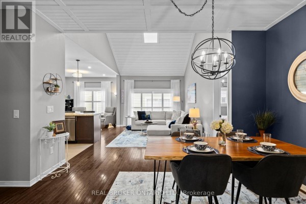 Living room with a large grey sectional sofa, coffee table, and artwork of a blue boat on a beach. - 3321 Beach Club Boulevard, Severn