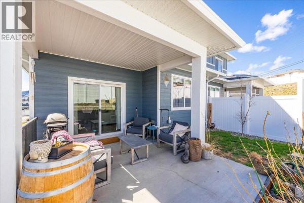 View of the blue duplex exterior with white garage doors and stone foundation. - 3321 Hawks Crescent, Westbank