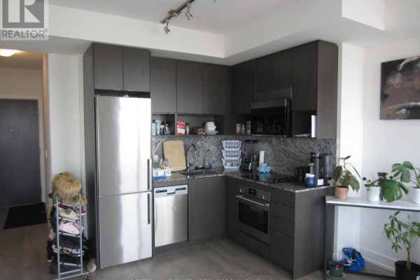 Corner kitchen with dark wood cabinets, stainless steel appliances, and potted plants on a console table. - 3325 - 9 Mabelle Avenue, Toronto