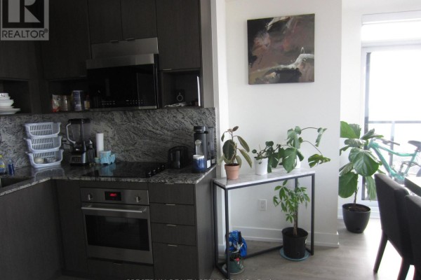 Dining area with a dark wood table and chairs, large windows, and a city view. - 3325 - 9 Mabelle Avenue, Toronto