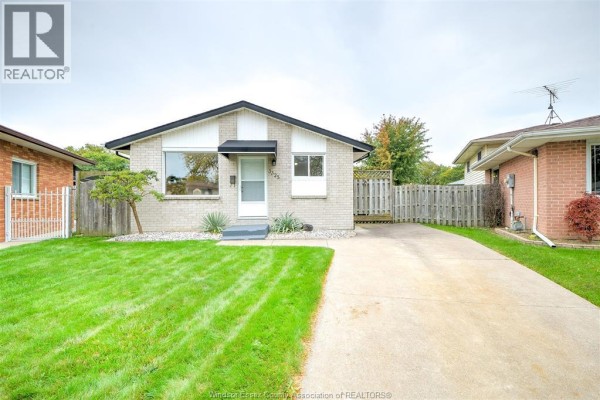 Slightly angled front view showcasing the bungalow's entrance and surrounding lawn. - 3325 Dolphin Court, Windsor