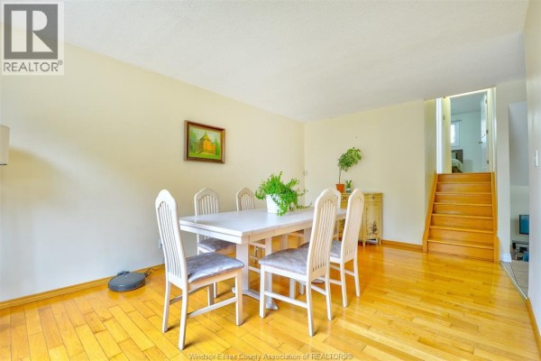 Dining room with a white table, chairs, hardwood floors, and stairs to upper level. - 3325 Dolphin Court, Windsor