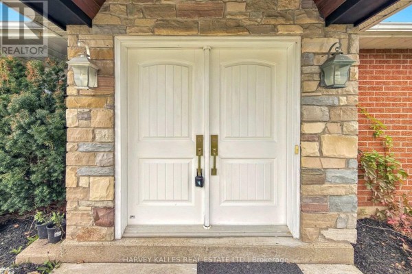 Close-up of white double front doors with brass hardware and stone surround. - 3327 Simcoe County 50 Road, Adjala Tosorontio