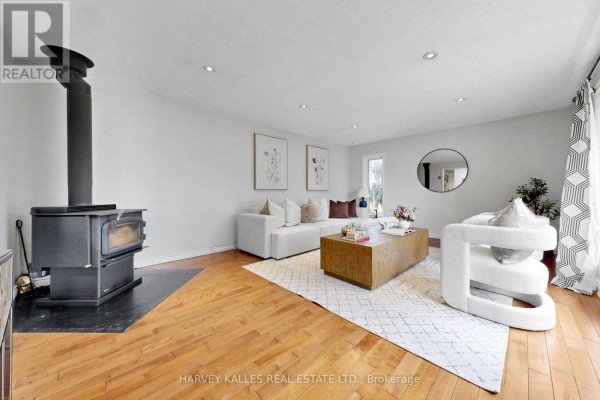 Living room with a wood-burning stove, white sectional sofa, and hardwood floors. - 3327 Simcoe County 50 Road, Adjala Tosorontio