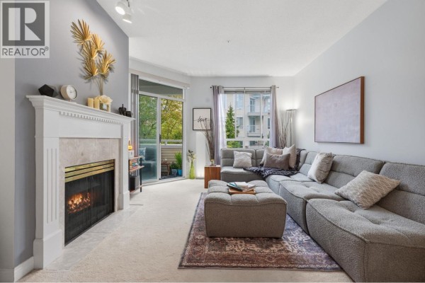 Living room featuring a fireplace, plush carpet, sectional sofa, and access to a balcony. - 333 383 E 37th Avenue, Vancouver