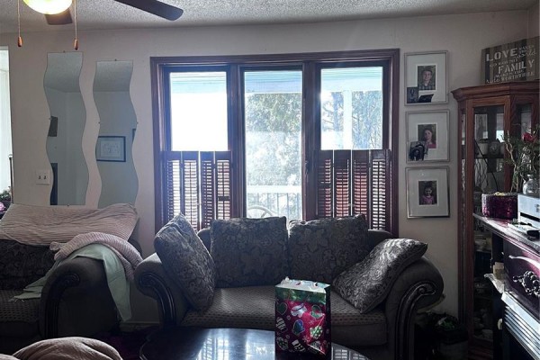 Living room with two sofas, patterned cushions, wooden shutters, and framed pictures. - 333 5th Avenue Se, Weyburn