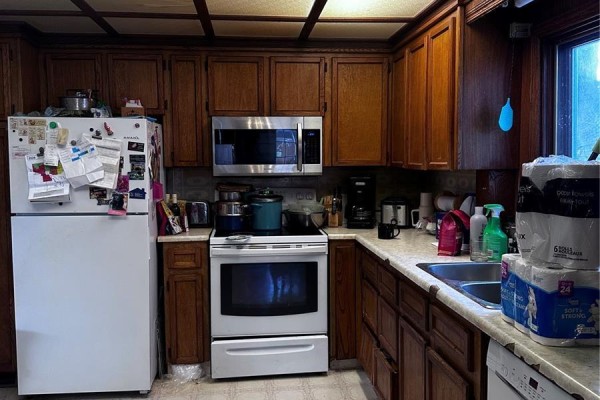 Kitchen with white refrigerator, dark wood cabinets, white stove, and laminate countertops. - 333 5th Avenue Se, Weyburn