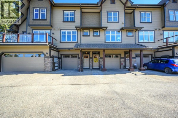 Bathroom with wood vanity, granite countertop, toilet, and tiled bathtub with shower. - 333 Longspoon Drive Unit# 26, Vernon