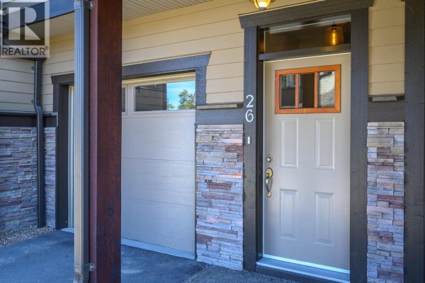 Bedroom with large window overlooking green trees and a cloudy blue sky. - 333 Longspoon Drive Unit# 26, Vernon
