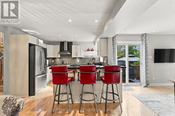 Kitchen with light wood cabinets, stainless steel appliances, and a breakfast bar with red stools. - 333 Riversedge Crescent, Ottawa