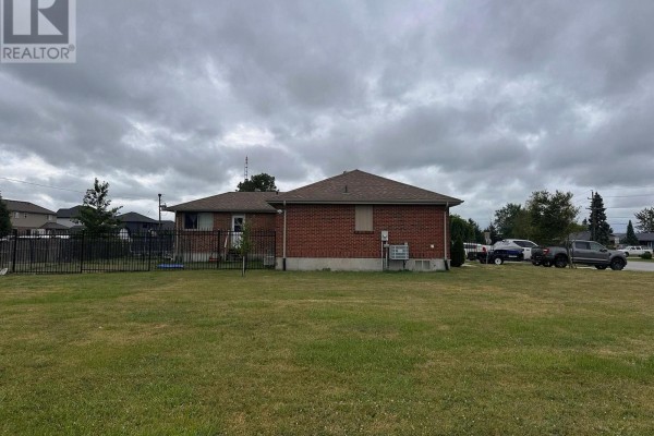 Rear exterior view of a brick bungalow with a fenced yard and overcast sky. - 33374 Richmond Street, Lucan Biddulph