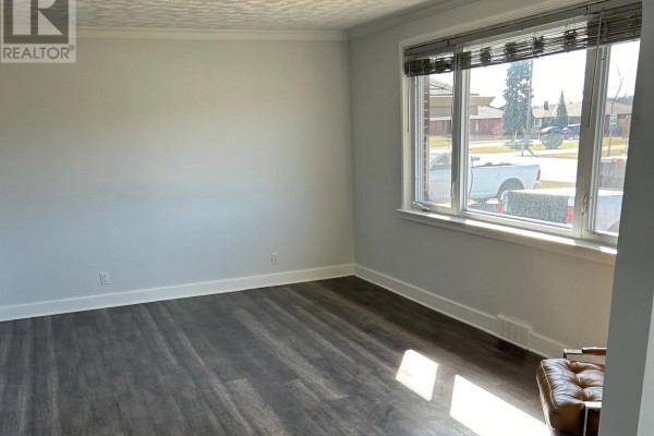 Living room with dark wood laminate flooring, white walls, and a large window. - 33374 Richmond Street, Lucan Biddulph