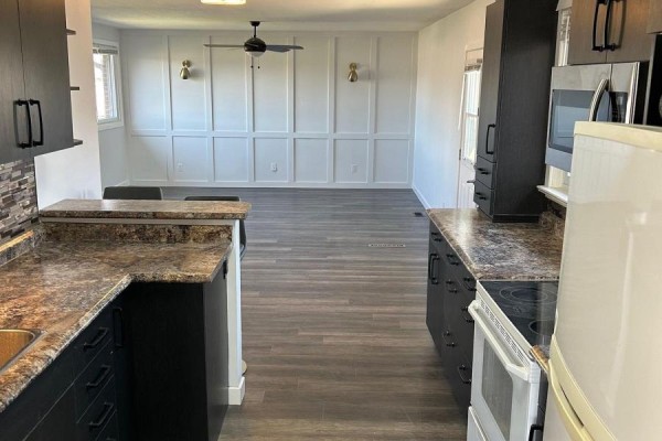 Kitchen with dark cabinets and granite counters overlooking a dining area with decorative paneling. - 33374 Richmond Street, Lucan Biddulph