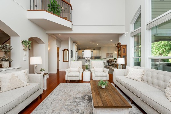Spacious living room with vaulted ceiling, grand staircase, fireplace, and views of the kitchen and dining area. - 3338 157a Street, Surrey