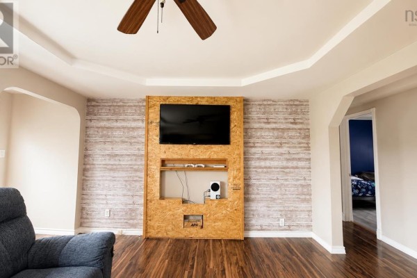 Living room with a large TV mounted on a textured wood panel wall and arched doorways. - 334 Park Road, Florence
