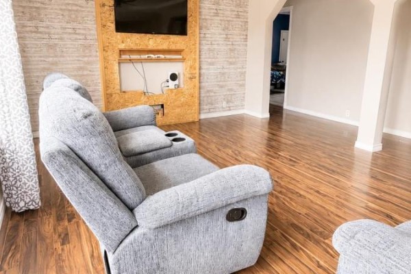 Close-up of a grey reclining sofa with cup holders in the living room with wood laminate flooring. - 334 Park Road, Florence