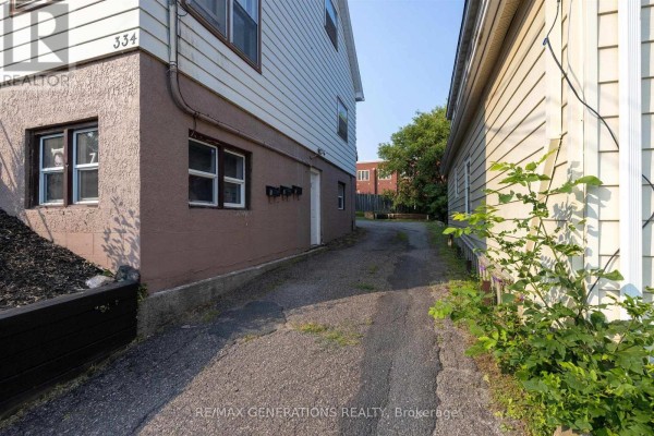 Side view of house showing basement windows, white siding and adjacent driveway. - 334 Pearl Street, Thunder Bay