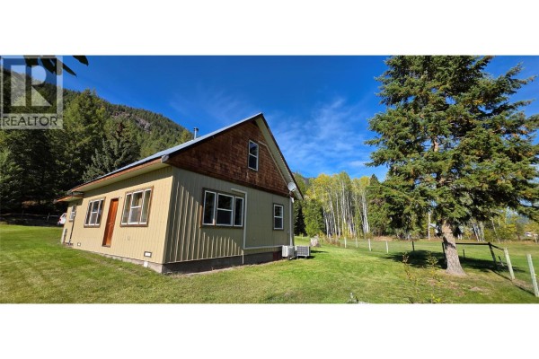 Side exterior of the house, showing green siding, wood trim, and a metal roof. - 3340 Christian Valley Road, Westbridge