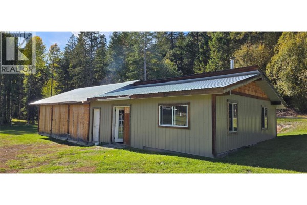Rear exterior of the house with a covered patio area and wood siding details. - 3340 Christian Valley Road, Westbridge