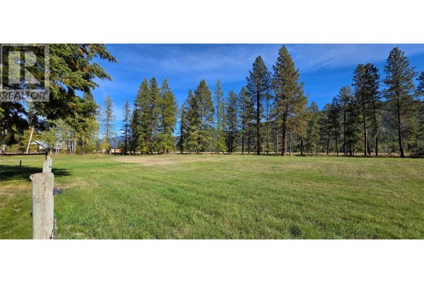 Expansive green field with scattered trees and a distant mountain view, under a blue sky. - 3340 Christian Valley Road, Westbridge