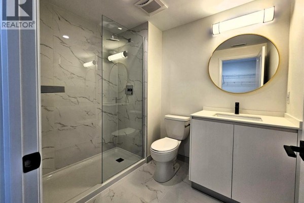Bathroom with a glass-enclosed shower with marble-look tile and a vanity with a round mirror. - 3340 Stella Crescent Unit# 517, Windsor