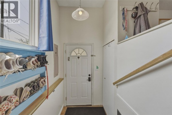 Interior view of a small foyer with a white door, shoe rack, and coat hooks on the wall. - 3343 Belaire Drive, Armstrong