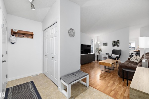 Interior entryway with double white closet doors, a bench, and a view into the living room. - 3344 24 Av Nw, Edmonton